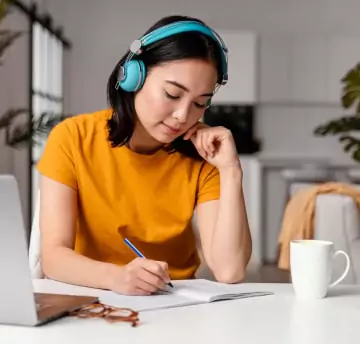 A girl writing on note while listening online lecture