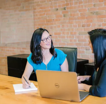 A female lawyer discussing with other women and writing on note.