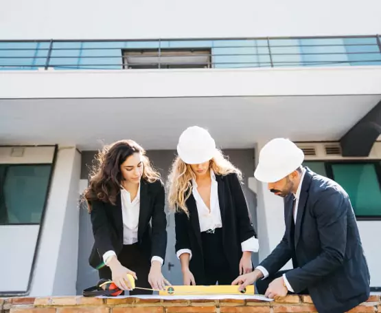 Three construction employees mapping design on paper