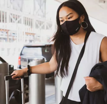A female wearing black mask and bag in hand