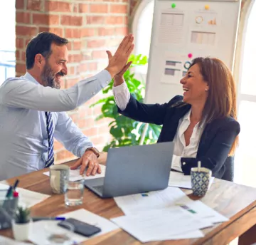 Two people are giving hi-fi and smiling while working in office