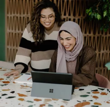 Two womens smiling while working on laptop